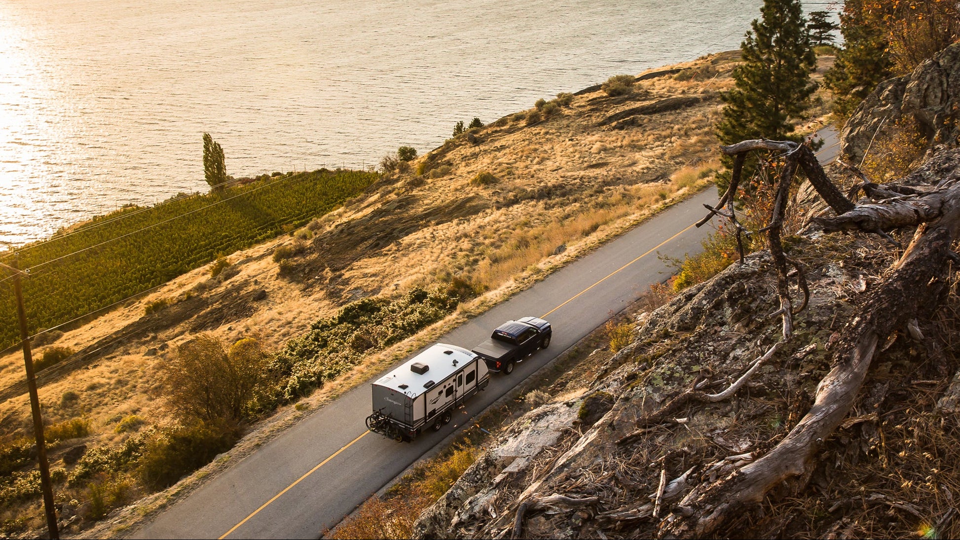 Scenic view of a lake with a road and vehicles at sunset.